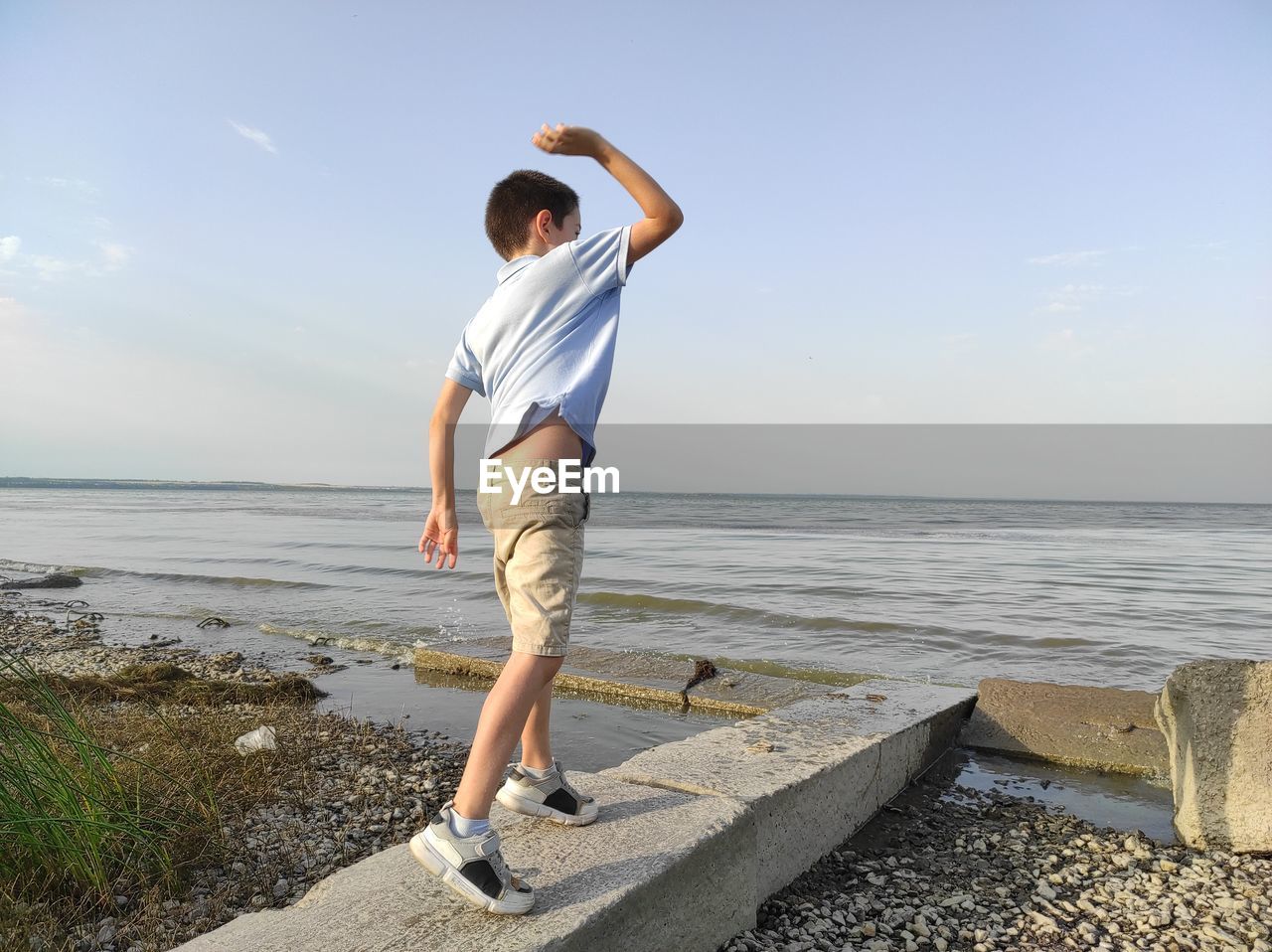 Boy throws stones into the sea