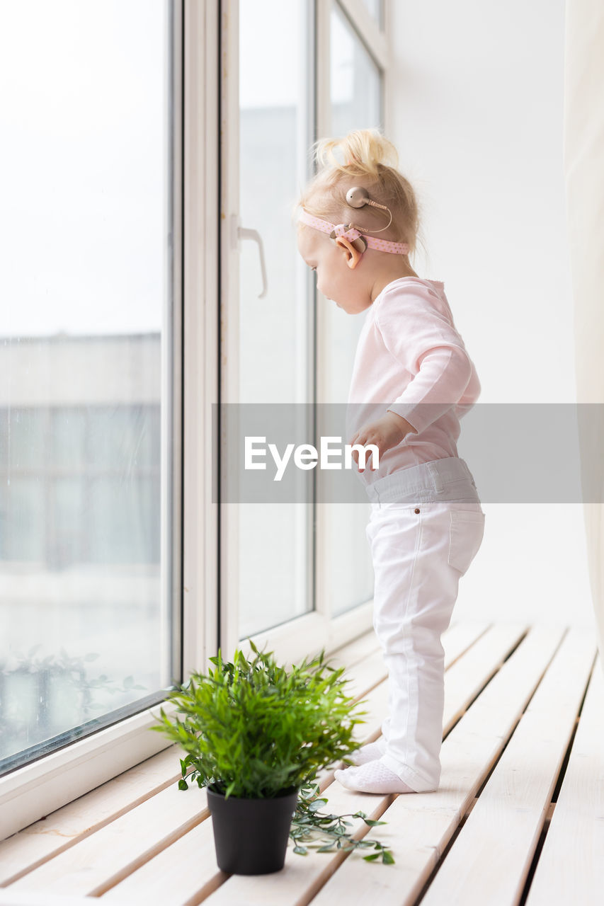 Full length of girl standing by window