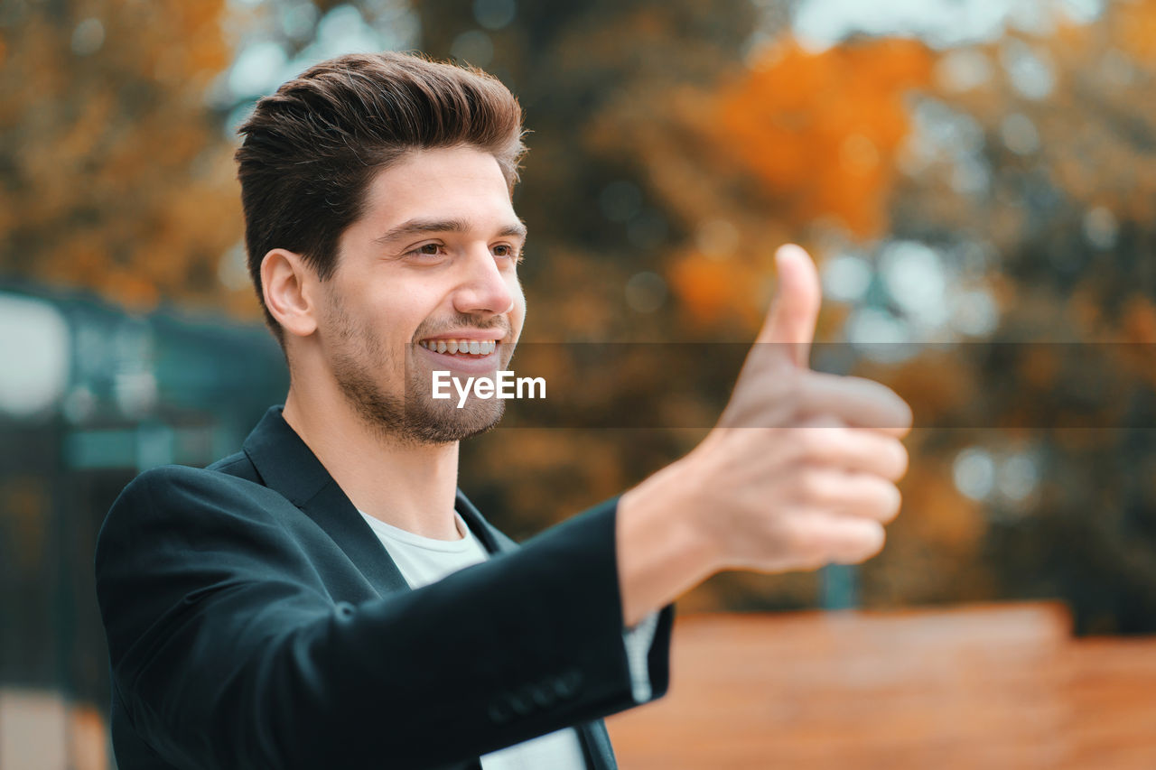 Smiling businessman showing thumbs up sign