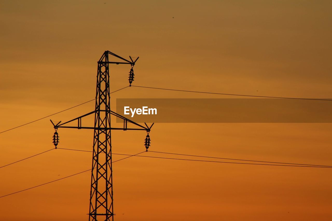 Low angle view of silhouette electricity pylon against sky during sunset