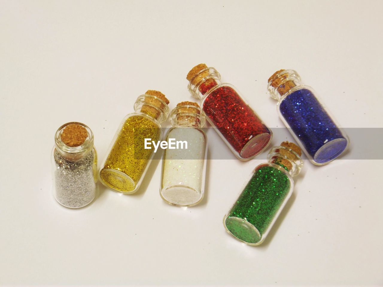 High angle view of multi colored sparkles in bottles on table