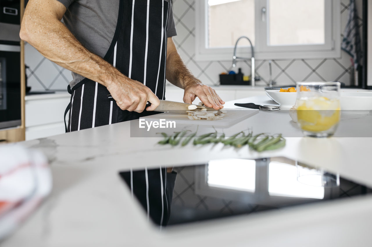 Man slicing mushroom on cutting board in kitchen at home