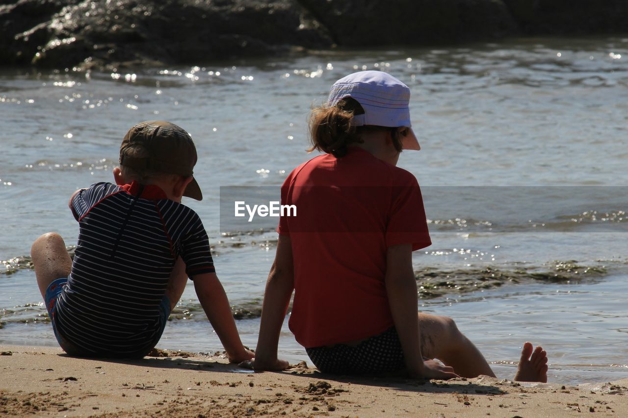 Rear view of children sitting at beach