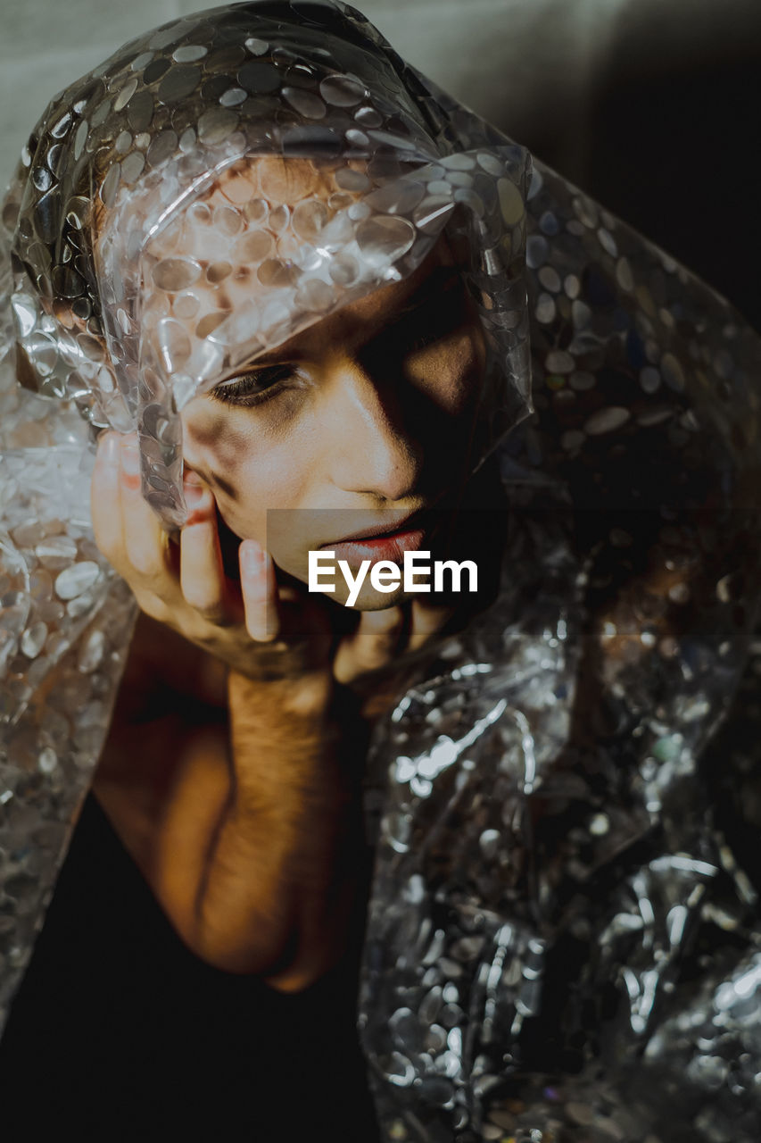 Close-up of young man sitting with plastic