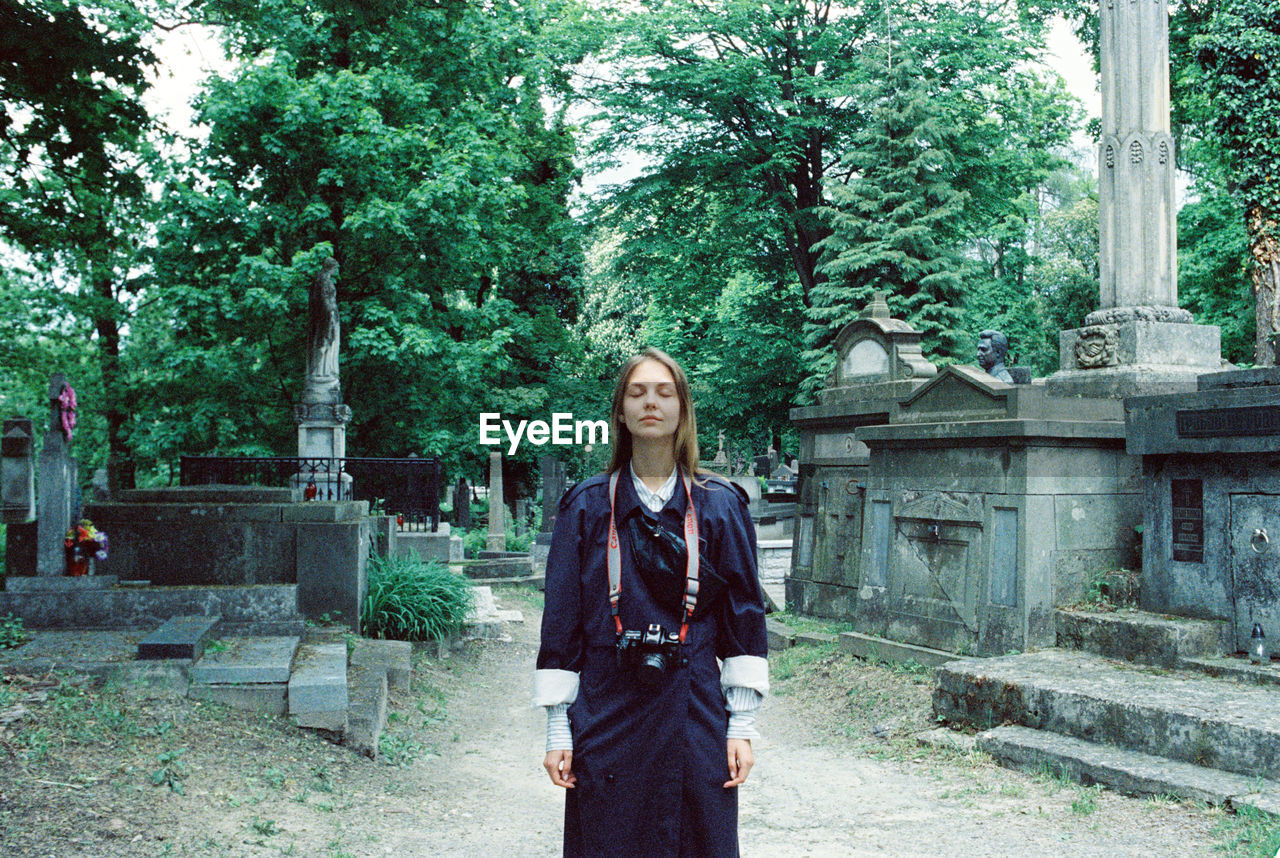 Portrait of a young woman standing against trees