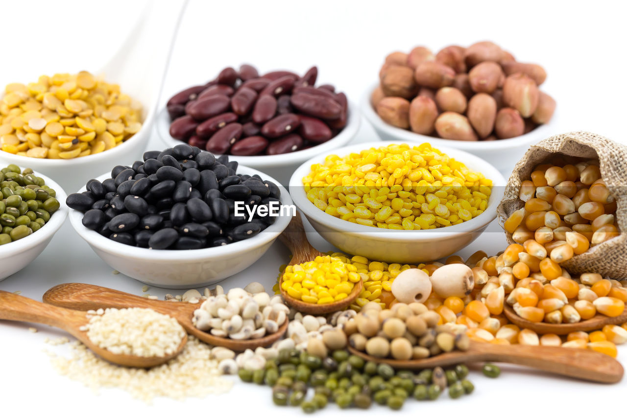A variety of grains, such as black beans, red beans, dehydrated corn on white background.