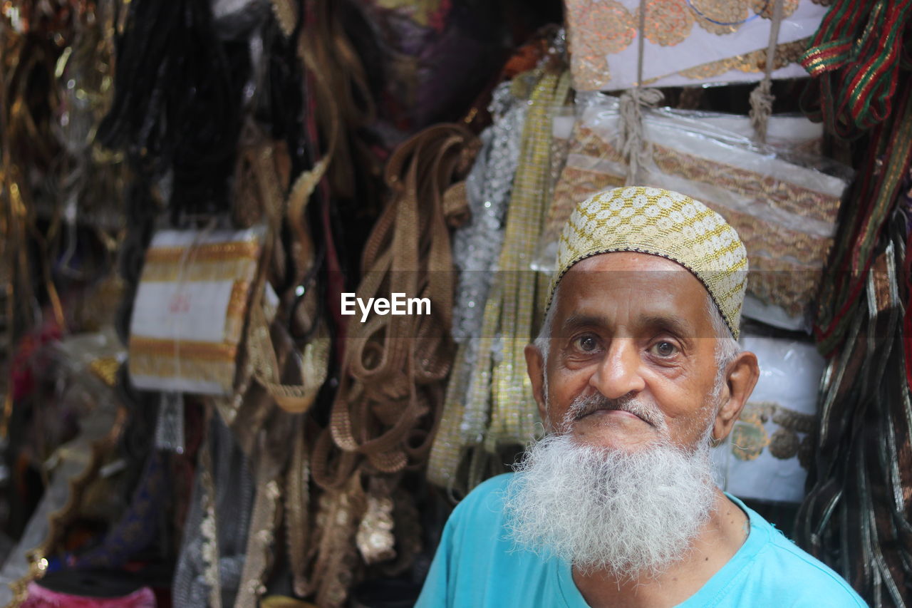 An old muslim man selling goods in his zari shop
