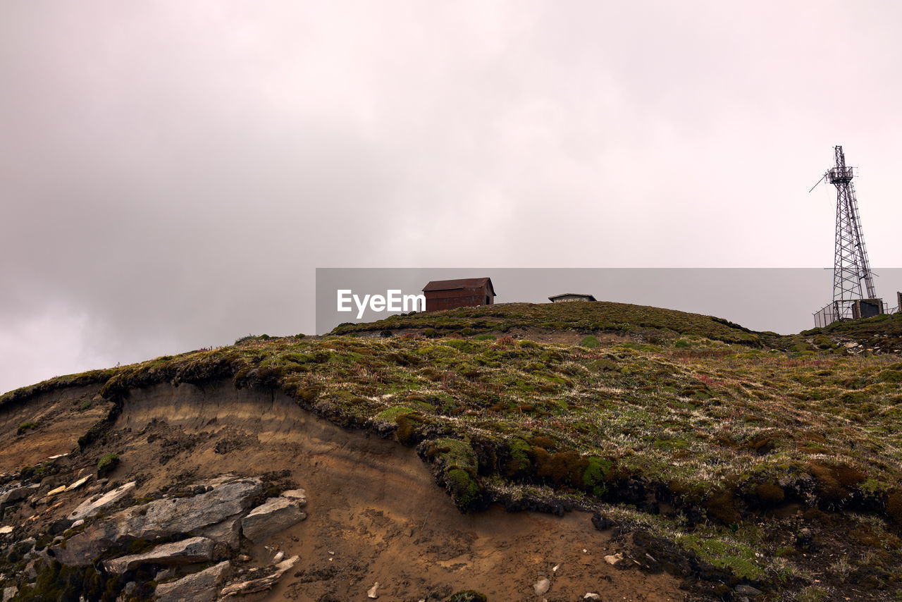 Low angle view of cabin on mountain against sky