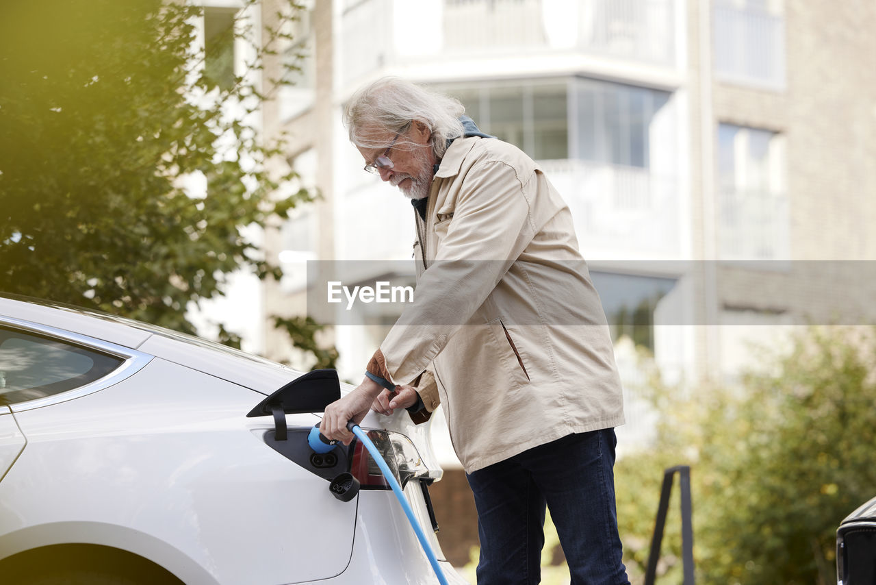 Senior man charging electric car