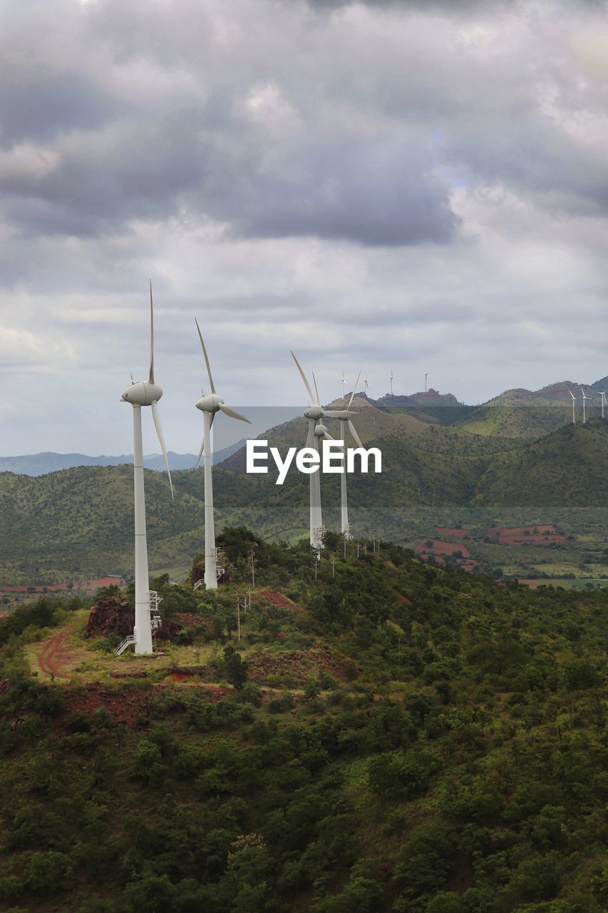 Wind turbines on field against sky