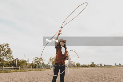 Cowgirl throwing lasso while standing at