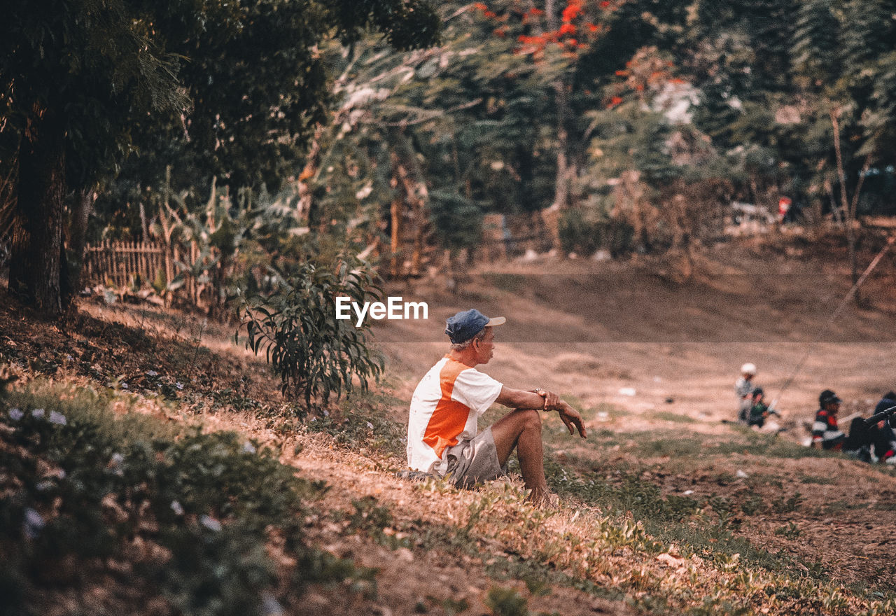 Side view of man sitting on field 