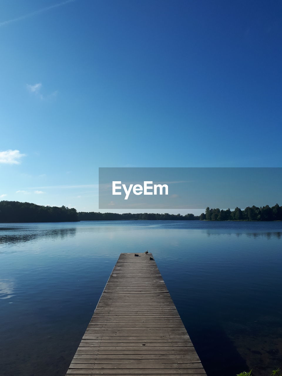 Pier over lake against blue sky