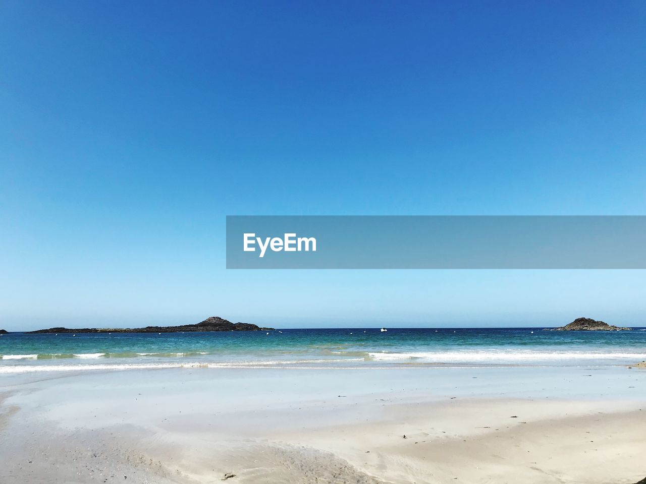 Scenic view of beach against clear blue sky