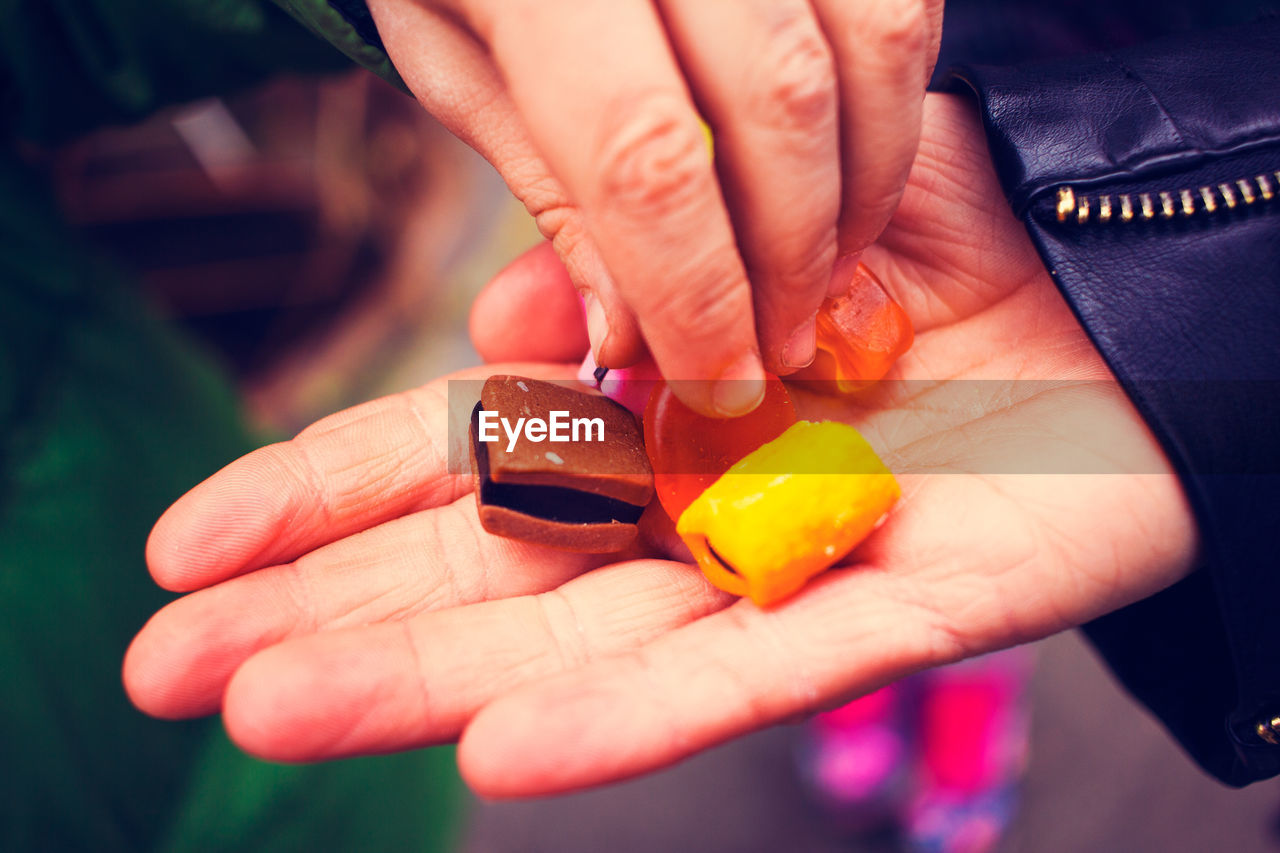 Cropped hand of man offering sweet food to friend