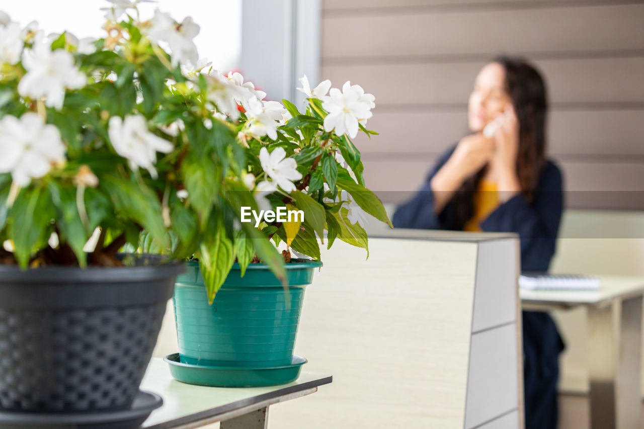 Defocused freelancer speaking on cellphone in a coffee shop with flowers