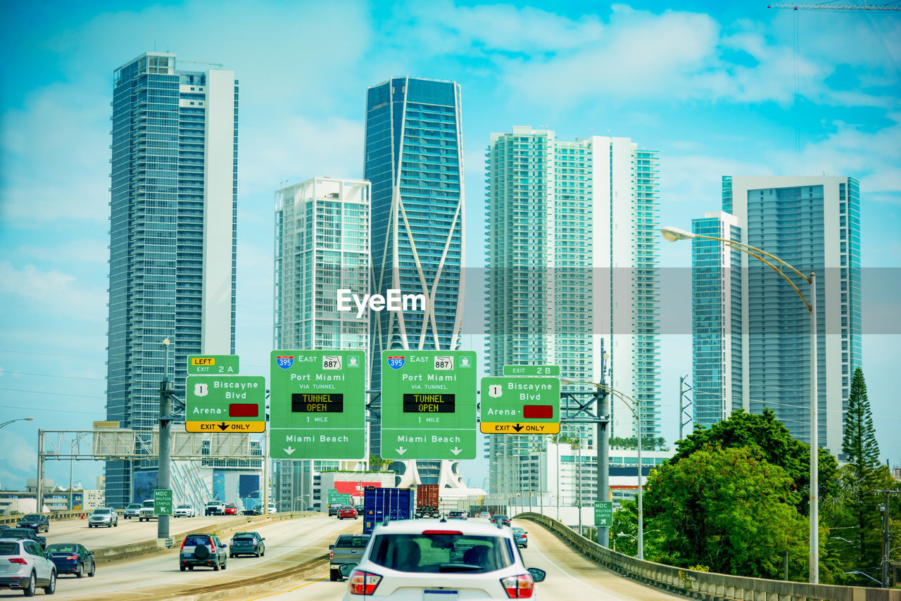 CARS ON ROAD BY BUILDINGS AGAINST SKY