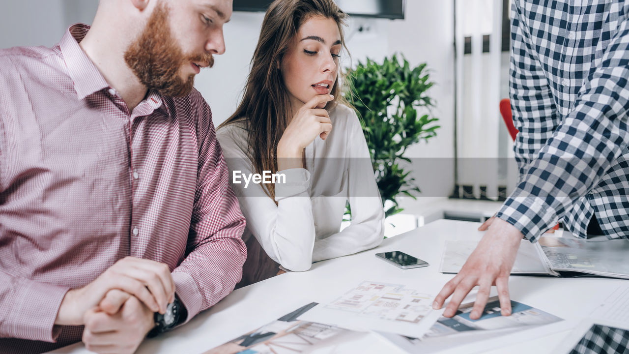 Young couple discussing over document while real estate agent explaining 