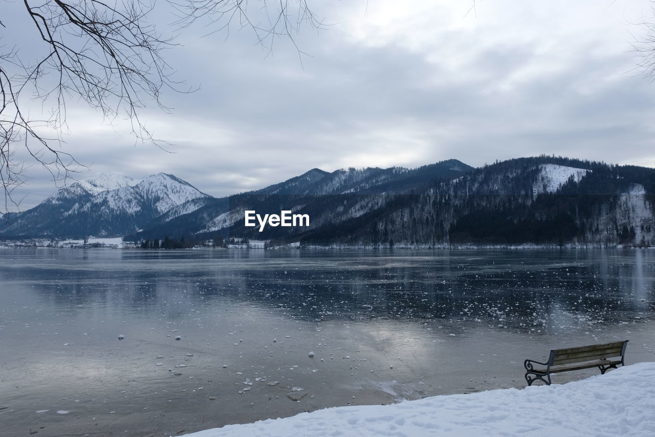 Scenic view of frozen lake by snowcapped mountains against sky