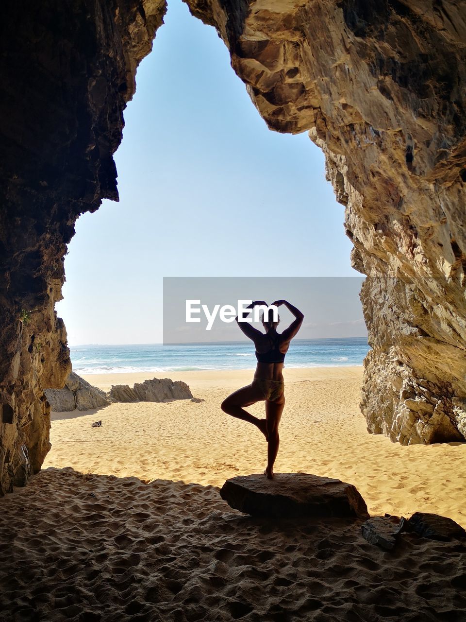 Full length of woman on rock at beach against sky