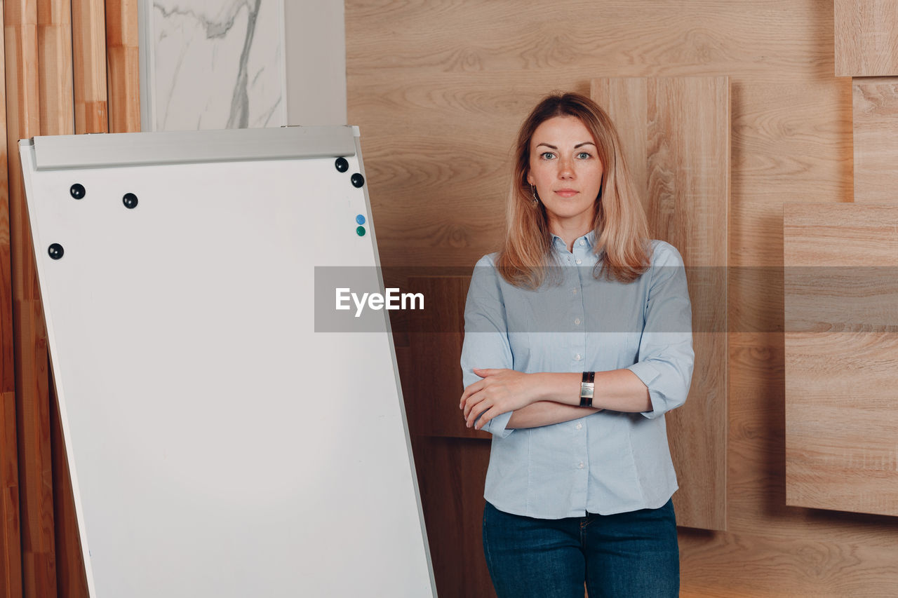 portrait of young woman using digital tablet while standing against wall