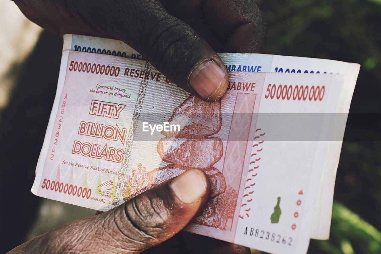 Cropped hands holding paper currencies