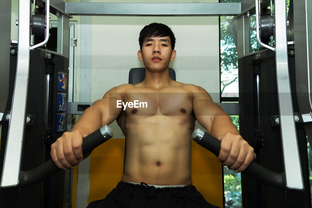 Portrait of shirtless man exercising at gym