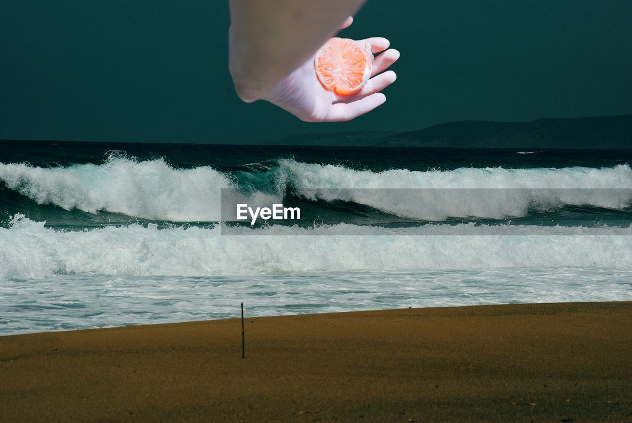 MIDSECTION OF PERSON HOLDING SEA BY WAVES