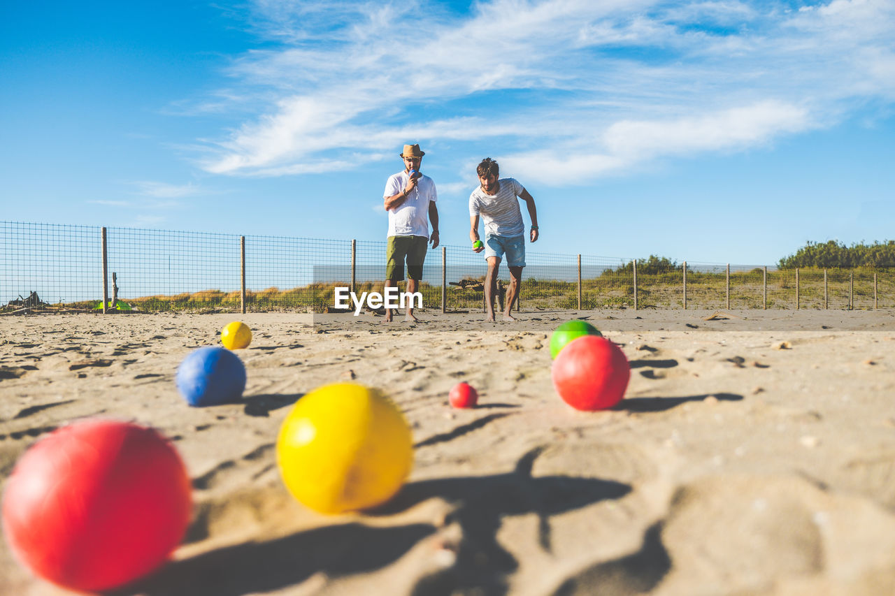 sky, land, beach, sand, nature, adult, men, sea, sunlight, holiday, women, togetherness, day, two people, full length, trip, female, leisure activity, vacation, cloud, ball, sports, summer, blue, outdoors, child, shore, fun, bonding, friendship, travel, childhood, copy space, emotion, lifestyles, water, sunny, standing