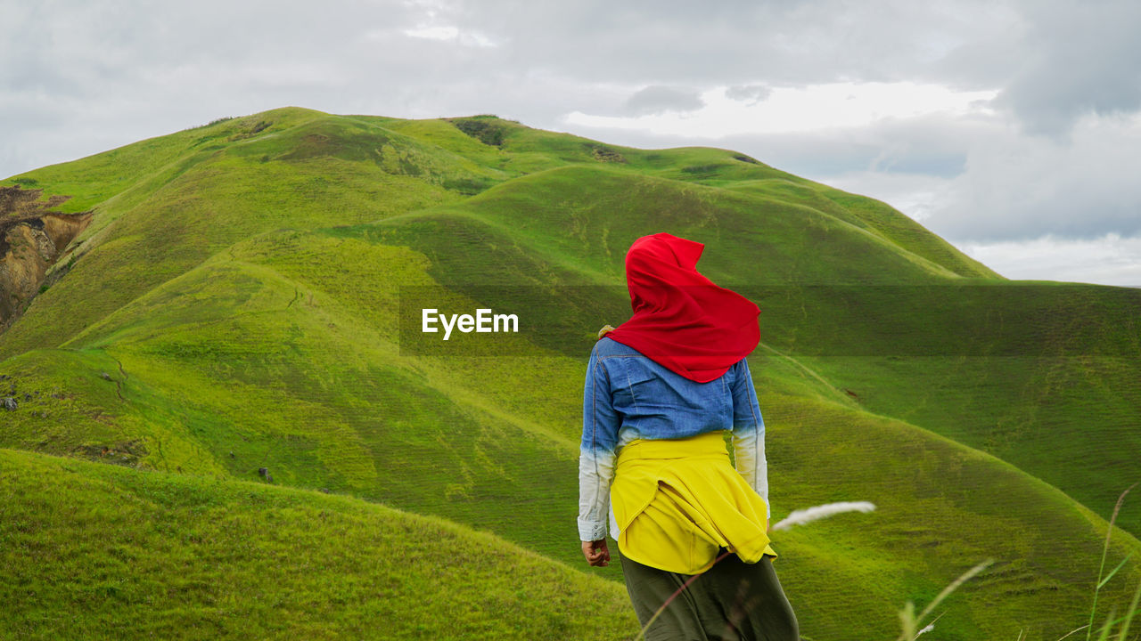 MAN STANDING ON GREEN LANDSCAPE