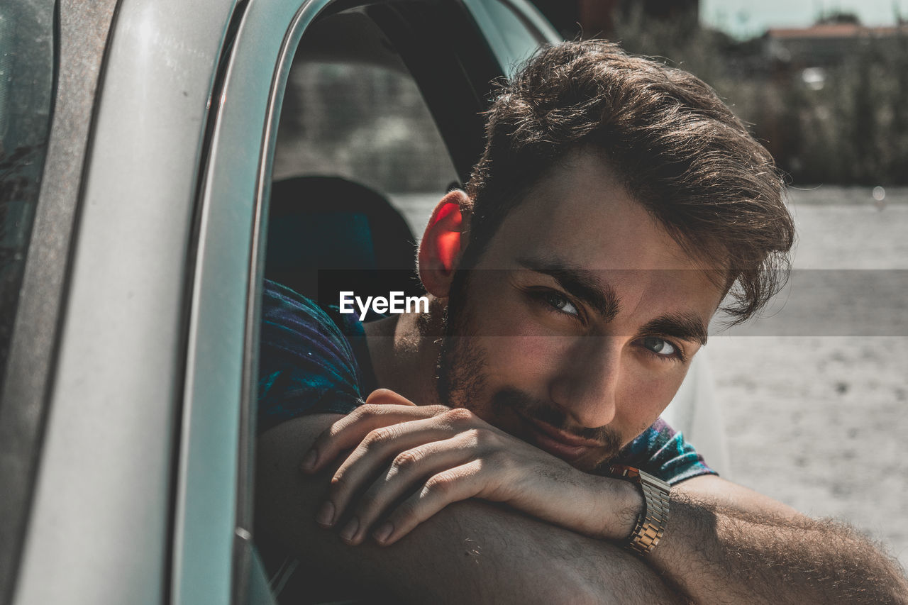 Close-up portrait of young man looking through car window