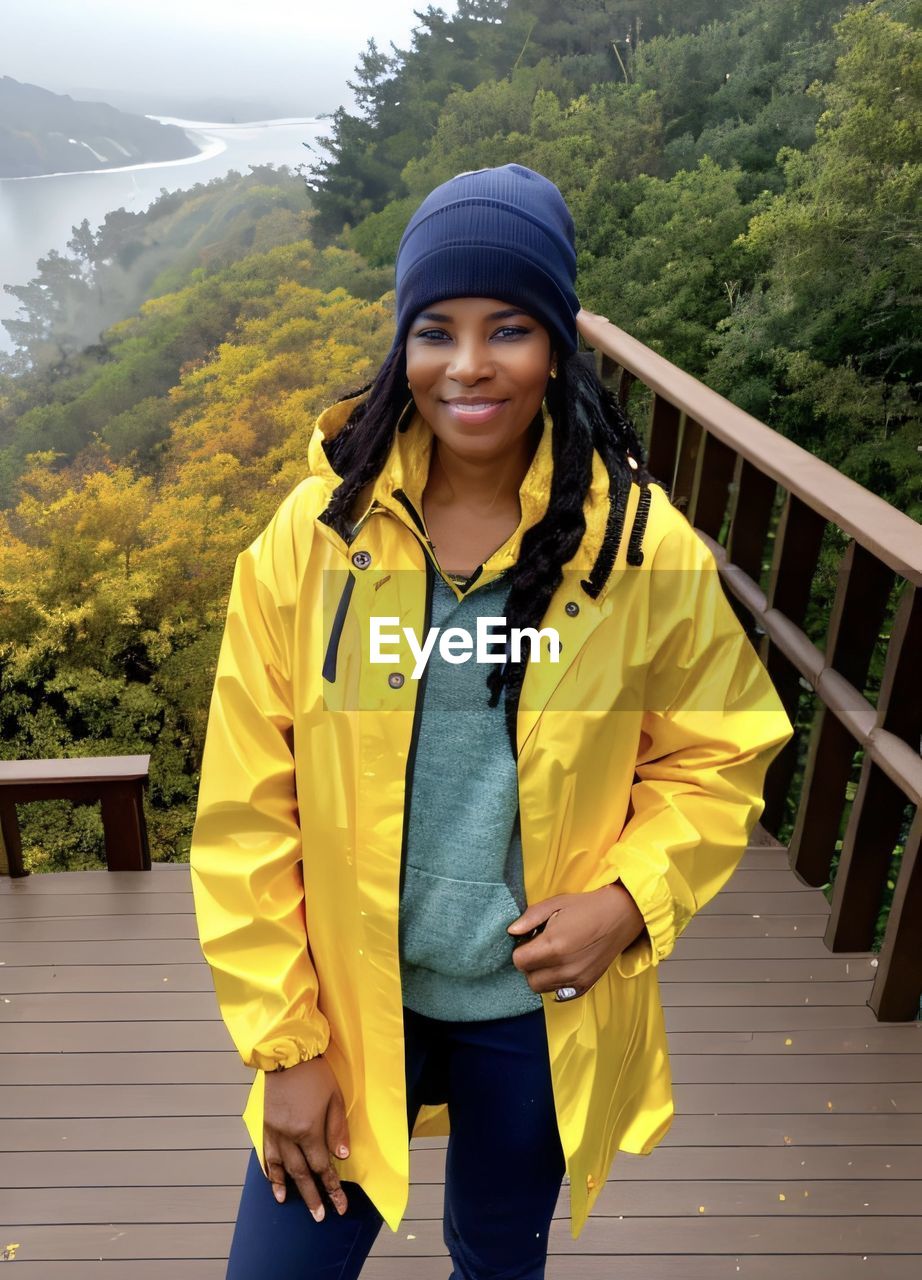 portrait of smiling young woman standing against mountain