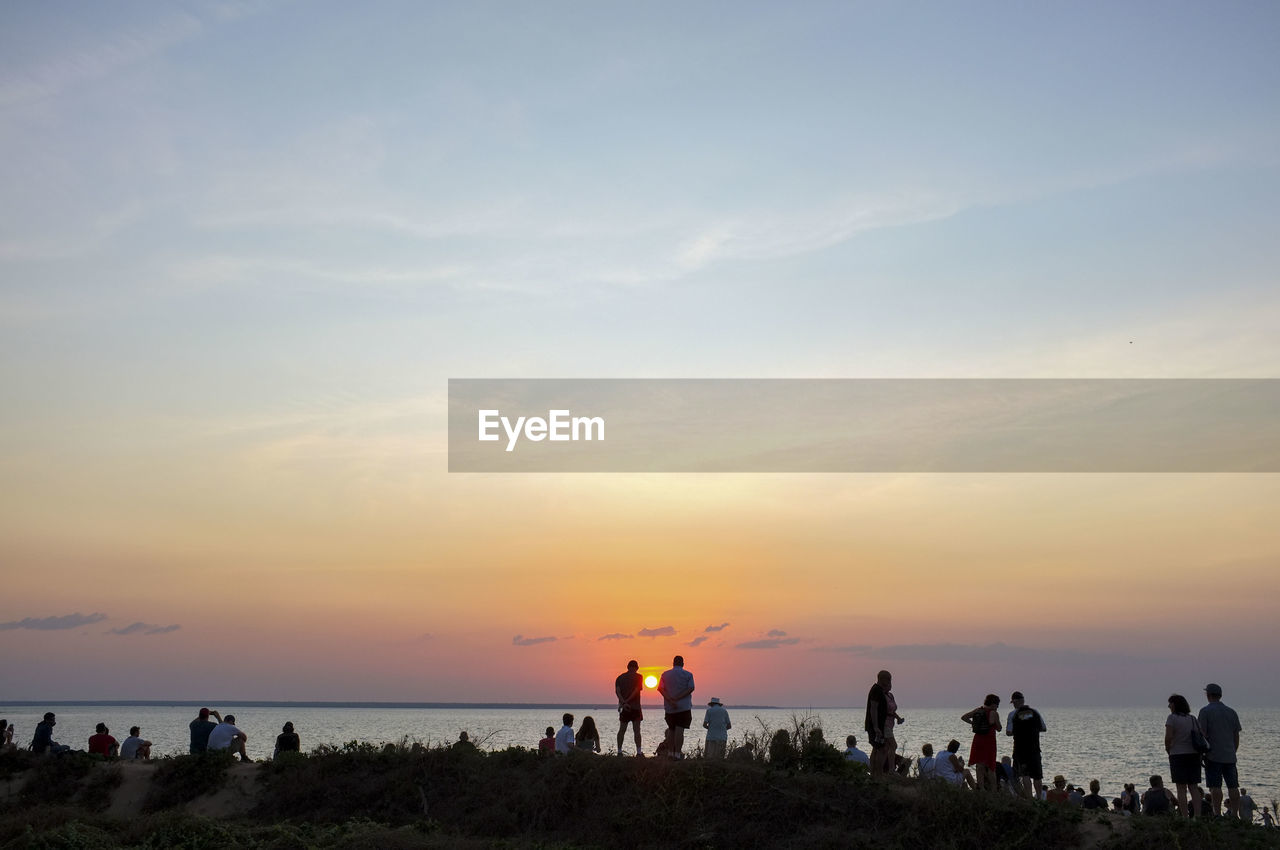 GROUP OF PEOPLE ON BEACH DURING SUNSET