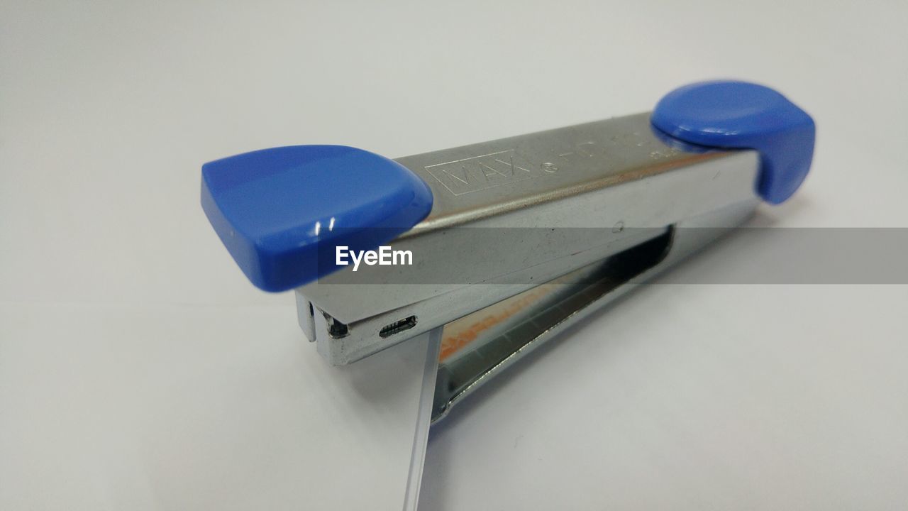 Close-up of stapler and paper against white background