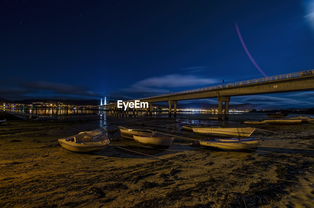 Illuminated bridge over sea against sky at night