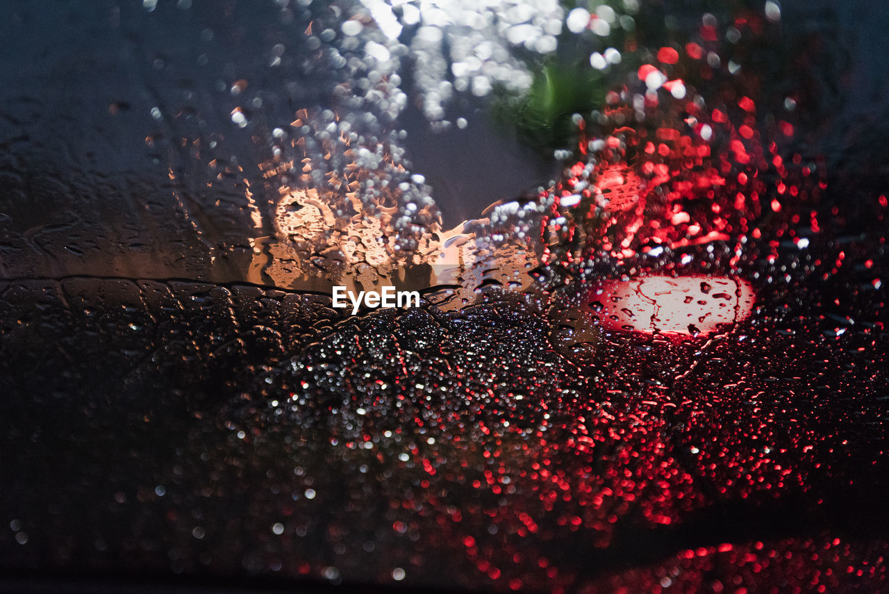 CLOSE-UP OF WET CAR WINDSHIELD AT NIGHT