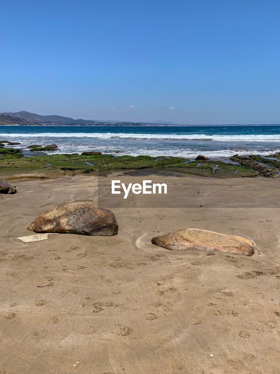 ROCKS ON BEACH AGAINST CLEAR SKY