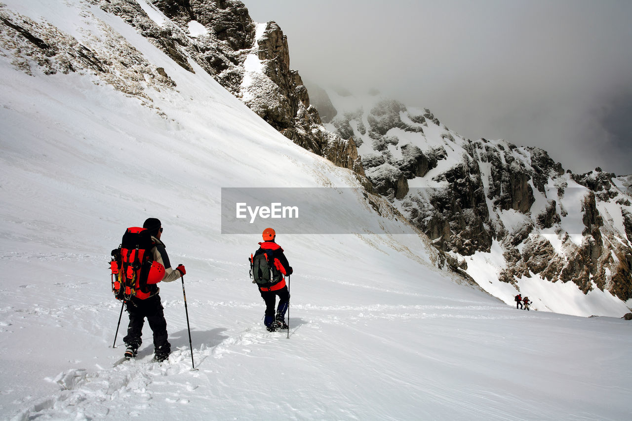 Rear view of men skiing on snowcapped mountain