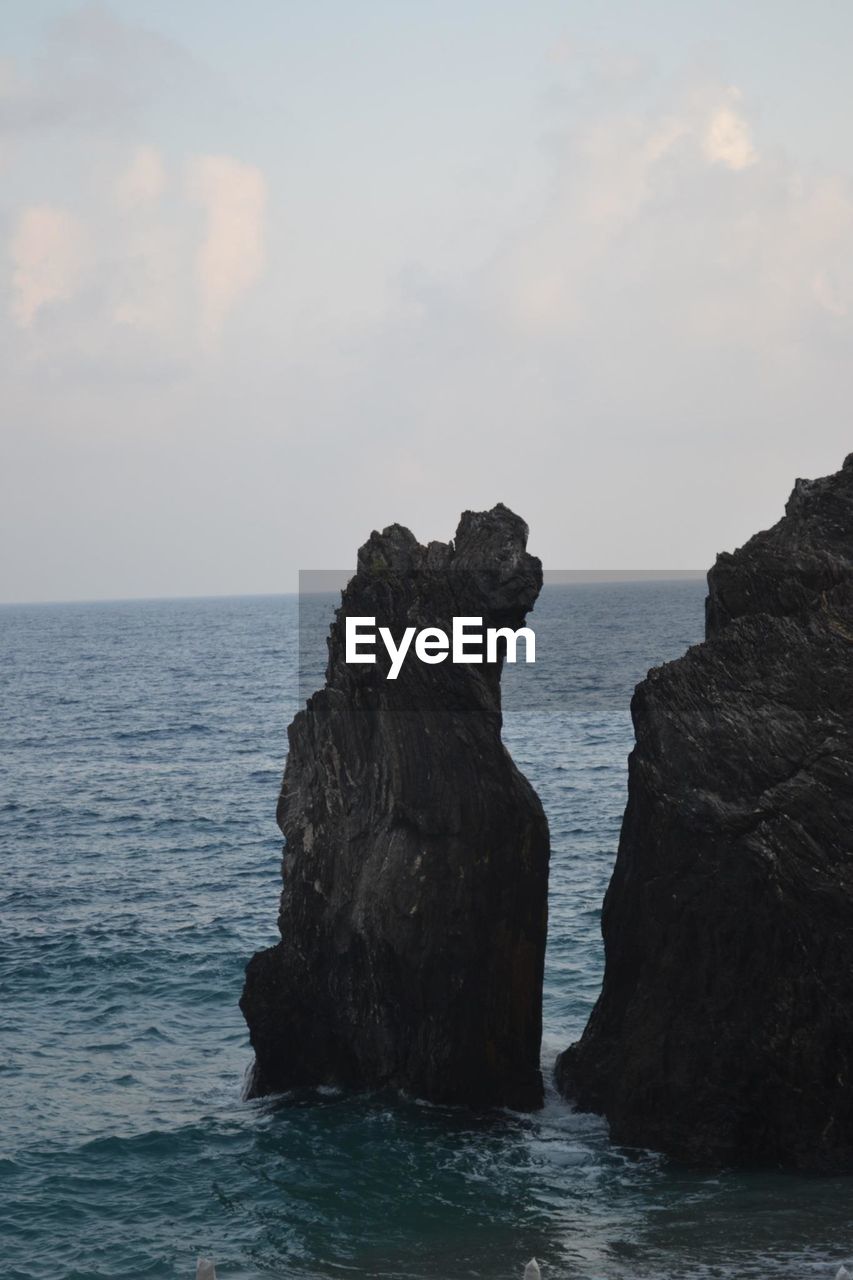 ROCKS IN SEA AGAINST SKY
