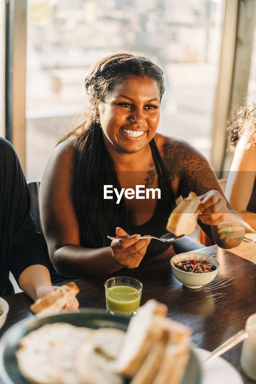 Smiling woman eating breakfast sitting at dining table in retreat center