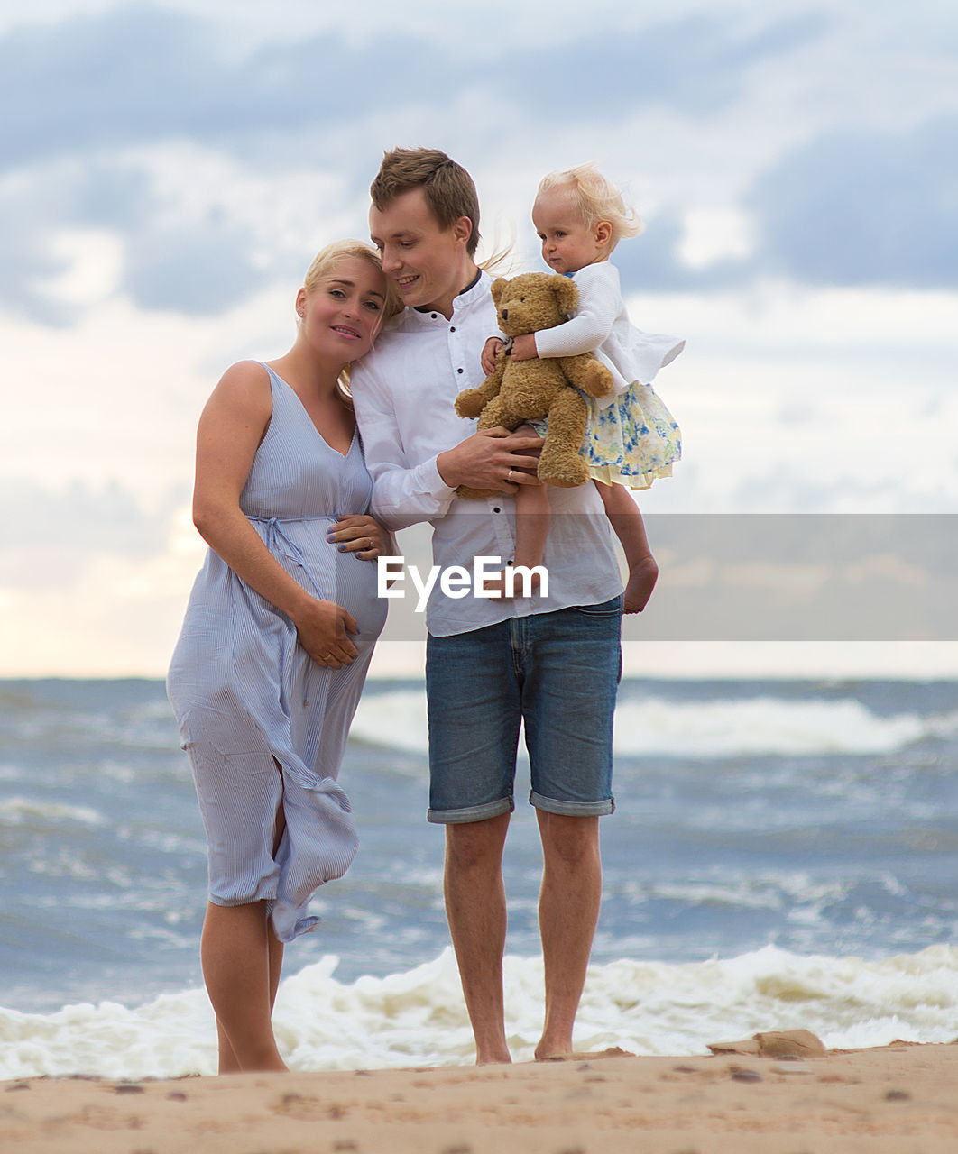 Pregnant woman with man and daughter at beach