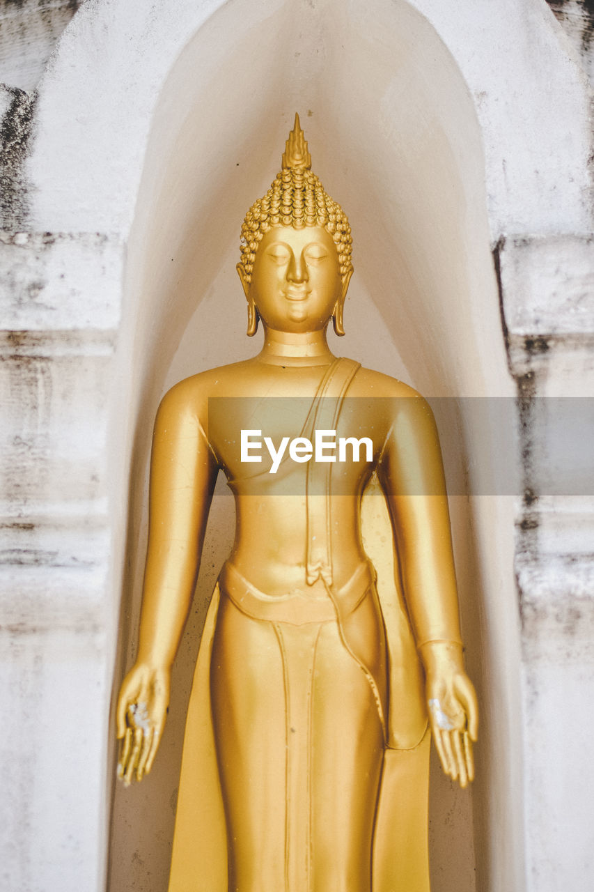 Close-up of golden buddha statue in niche