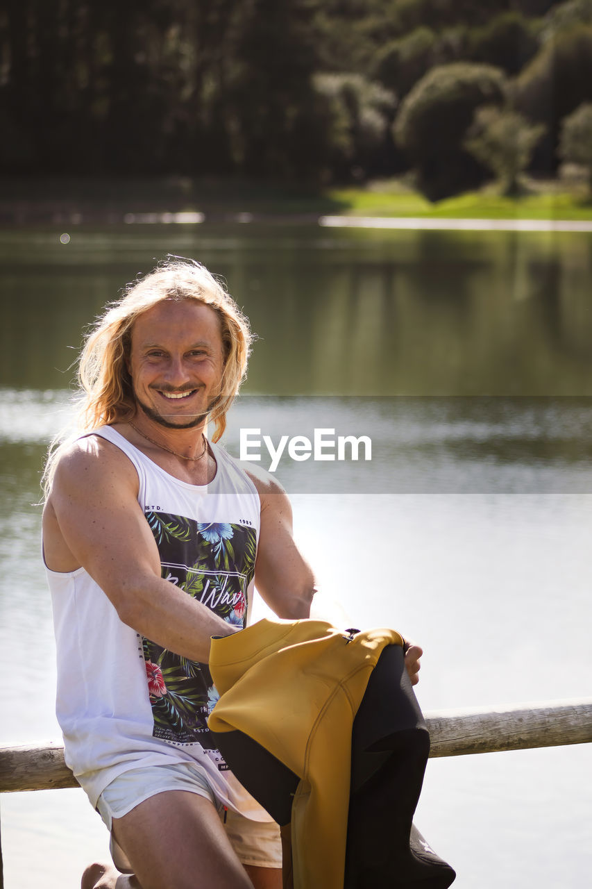 Happy man in park with forest and lake background at sunset