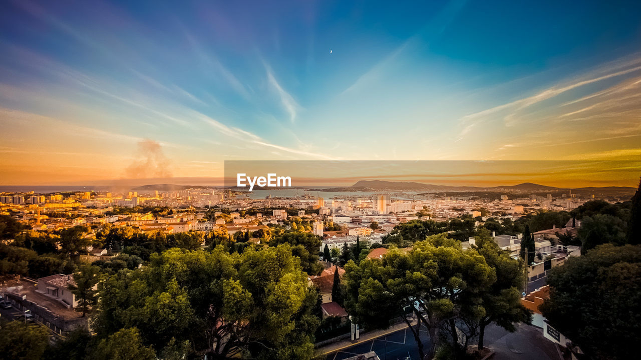 HIGH ANGLE SHOT OF TOWNSCAPE AGAINST SKY DURING SUNSET