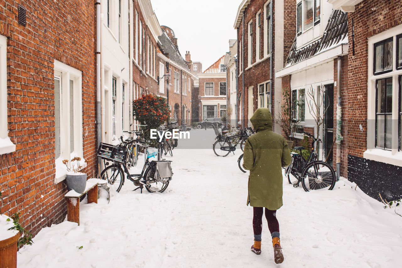 Full length rear view of woman walking in city during winter