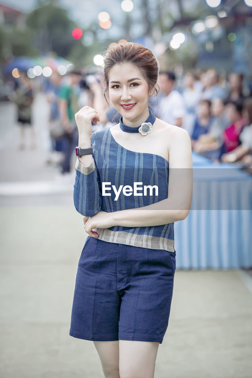 PORTRAIT OF SMILING WOMAN STANDING OUTDOORS