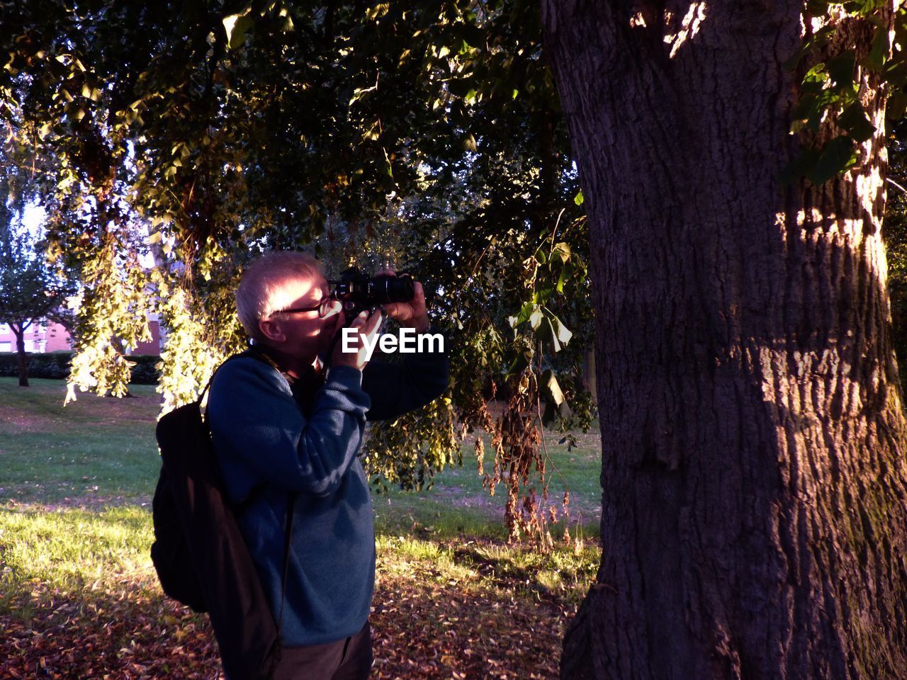 Mature man photographing tree