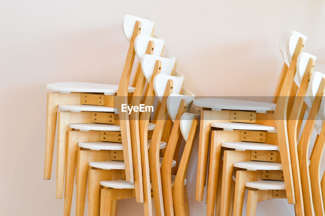 Stack of empty wooden chairs against wall