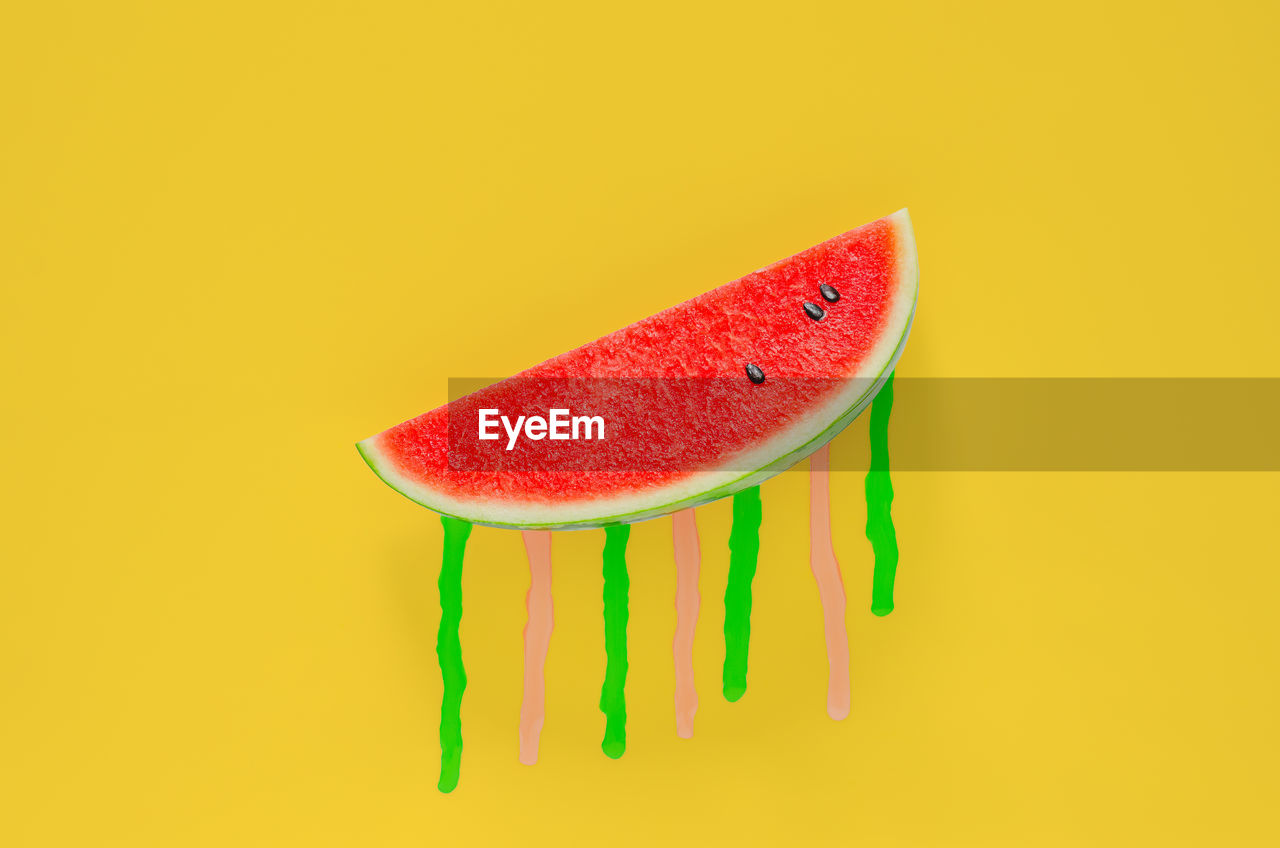 Watermelon with poster color drop on yellow background. minimal summer fruit concept.