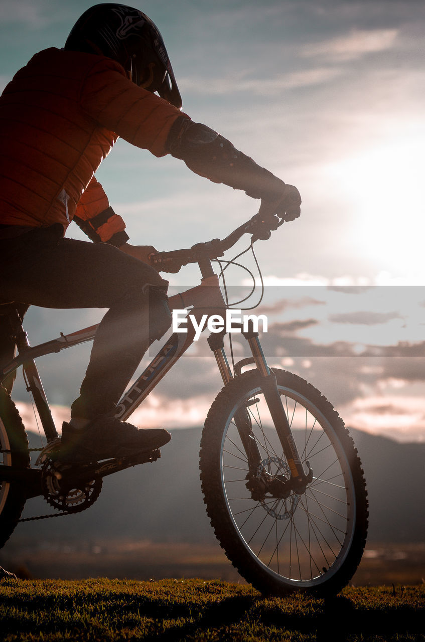 SIDE VIEW OF MAN RIDING BICYCLE AGAINST SKY